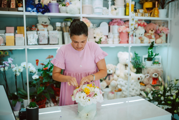 Nuori houkutteleva brunette valkoihoinen nainen kukkakauppa vaaleanpunainen mekko järjestää kukkakimpun kukkakauppa - Valokuva, kuva