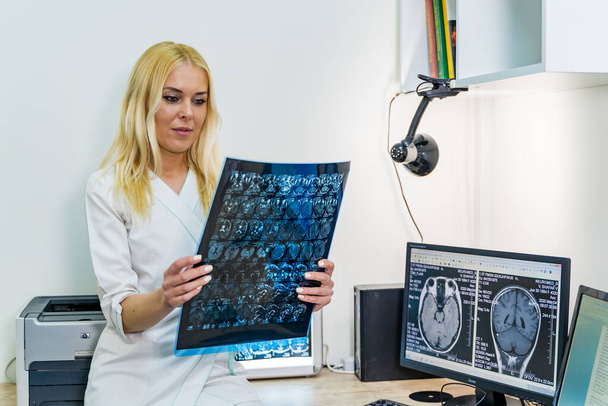 Žena lékař čtení rentgen obraz v blízkosti magnetické rezonance zobrazovací stroj. - Fotografie, Obrázek