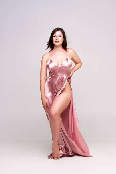 Sexy woman in pink dress with deep neckline in studio on gray background, full-length portrait - Foto, Imagen