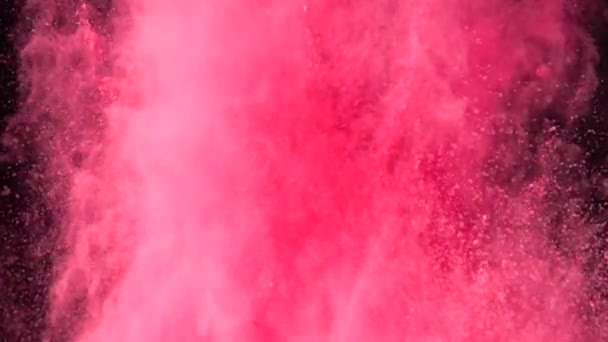 Explosión en cámara súper lenta de colorido polvo rojo sobre fondo oscuro aislado. Los bultos de polvo vuelan hacia arriba y se mezclan con el humo. - Imágenes, Vídeo
