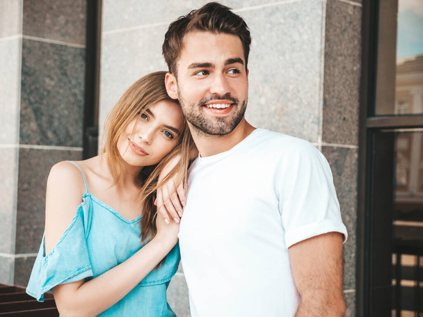 Portrait of smiling beautiful woman and her handsome boyfriend. Woman in casual summer jeans dress. Happy cheerful family. Female having fun. Couple posing on the street background - Valokuva, kuva