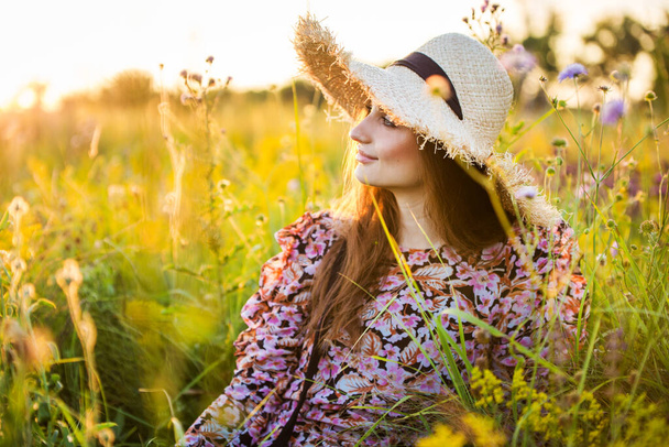 young beautiful european girl in the setting sun, on the field,in hat - 写真・画像