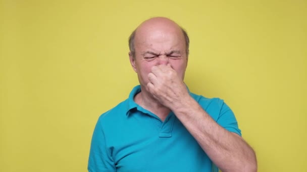 Homem hispânico sênior segurando seu nariz contra por causa de um mau cheiro
 - Filmagem, Vídeo