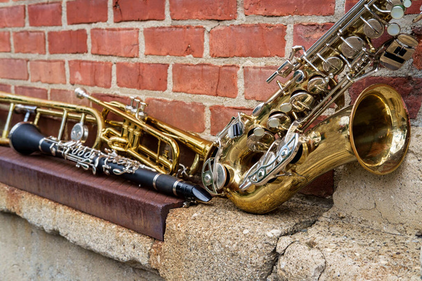 Muziekinstrumenten waaronder trombonettrompetklarinet en saxofoon op bakstenen muur buiten de Jazz Club - Foto, afbeelding