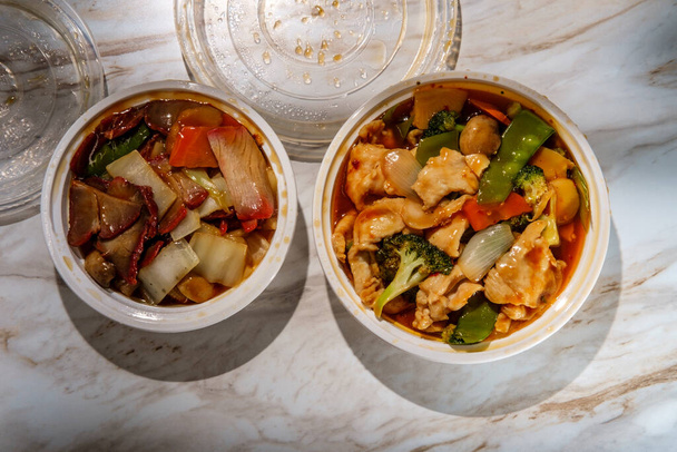 Szechuan-Huhn und Schweinebraten mit gemischtem Gemüse in Plastikbehältern zum Mitnehmen - Foto, Bild