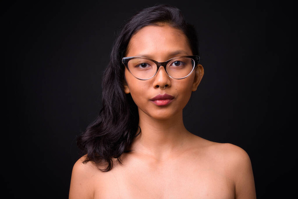 Siyah arkaplana karşı sağlık ve güzellik konsepti olarak tişörtsüz genç ve güzel Asyalı kadının stüdyo çekimi. - Fotoğraf, Görsel