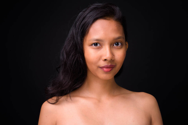 Studio shot van jonge mooie Aziatische vrouw shirtless als gezondheid en schoonheid concept tegen zwarte achtergrond - Foto, afbeelding