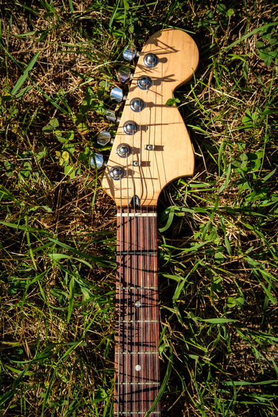 Blauwe elektrische gitaar in gras op een zonnige zomerdag - Foto, afbeelding
