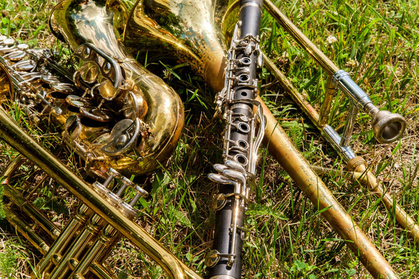Instrumenty muzyczne, w tym trąbka na trąbce klarnet i saksofon leżały na trawiastym polu na festiwalu muzycznym - Zdjęcie, obraz