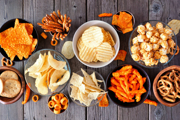 Assortment of salty snacks. Top view table scene on a dark wood background. - 写真・画像