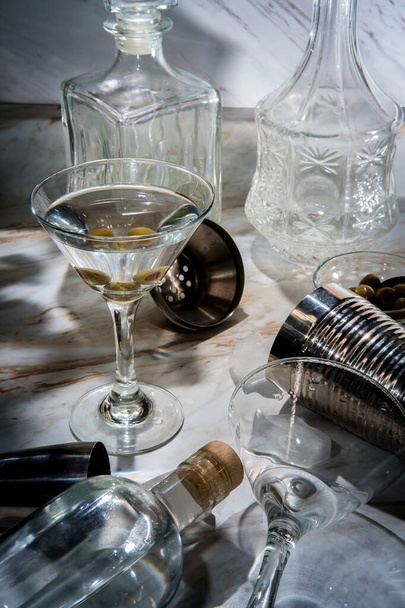 Making dirty gin martini shaken served straight up and garnished with green olives - 写真・画像