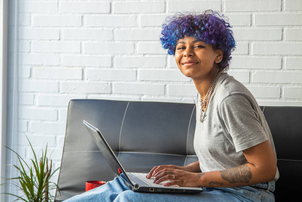 young african american woman using laptop on sofa at home - Foto, Imagen