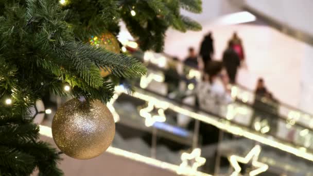Arany karácsonyi dekoráció a bevásárlóközpontban. Az emberek a mozgólépcsőn, az ünnepi üzleti központban, újévi vásárlásokat végeznek.,. - Felvétel, videó