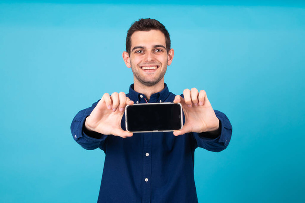 homem bonito sorrindo mostrando tela do telefone móvel isolado
 - Foto, Imagem