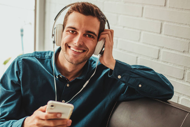 smiling young man with headphones and mobile phone - Fotó, kép