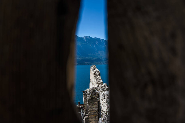 pohled na jezero garda mezi skalami zdí starých citrónových domů v blízkosti Limone sul Garda, Brescia Itálie - Fotografie, Obrázek