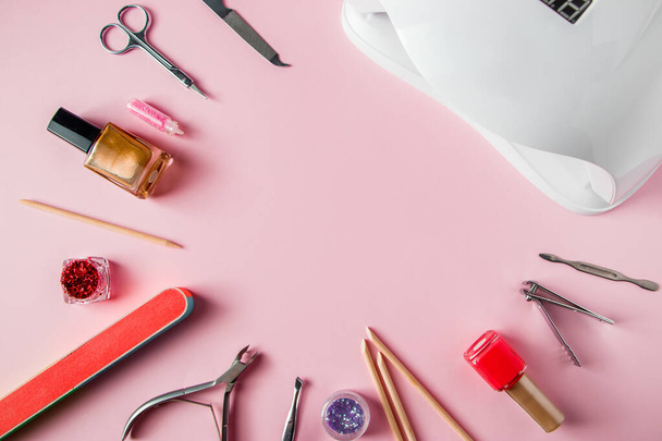 ピンクの背景にマニキュアとネイルケアのためのツールのセット。美容室での職場。テキストの場所. - 写真・画像