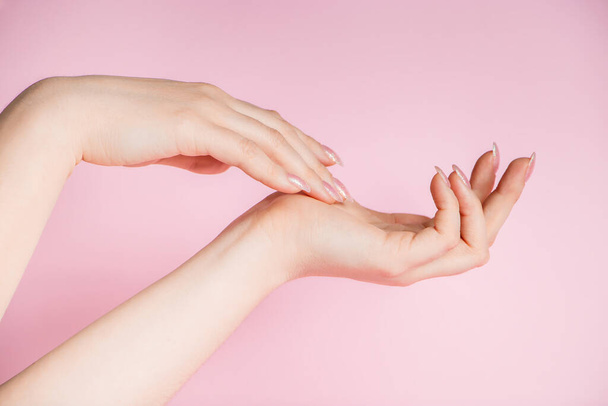 Hermosas manos femeninas sobre un fondo rosa. Spa y concepto de cuidado corporal. Imagen para publicidad. - Foto, imagen