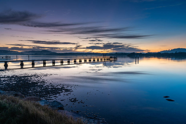 Sunrise waterscape with wharf, high cloud and reflections at Woy Woy Waterfront on the Central Coast, NSW, Australia. - Photo, Image