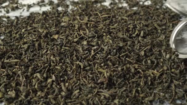 Tea strainer rakes in dried rolled green tea leaves on a white old wooden table - Video