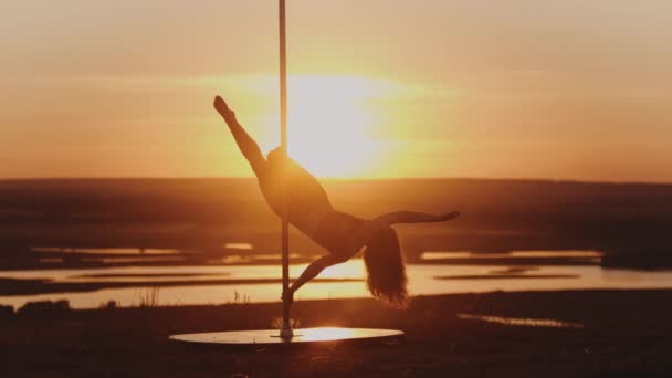 Pole Dance bei Sonnenuntergang - junge Frau hält sich kopfüber an der Stange - Filmmaterial, Video