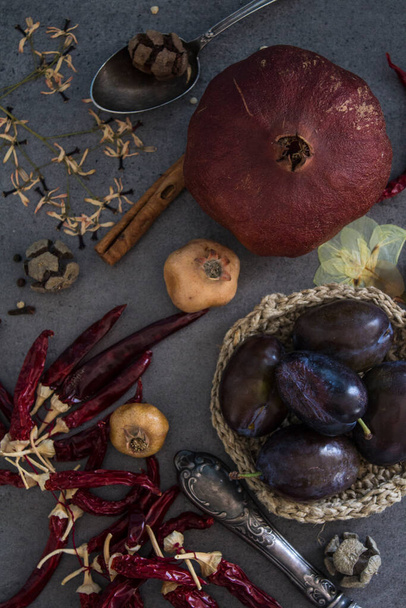 Csendélet szárított gyümölcsökkel, zöldségekkel és gyógynövényekkel sötétszürke textúrájú háttérrel. Top view fotó a különböző tárgyakat. Őszi színek. - Fotó, kép