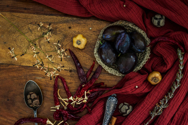 Still life with plums and dried herbs on wooden table. Top view photo of large group of objects. Autumn mood photo.  - Fotoğraf, Görsel