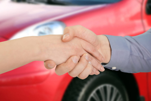 Woman buying car and shaking hands with salesman against blurred auto, closeup - Foto, Bild