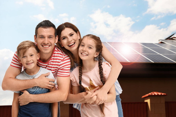 Happy family near their house with solar panels. Alternative energy source - 写真・画像