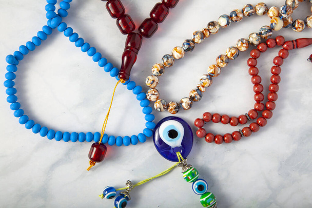 Une collection aléatoire d'une variété de perles de prière (tesbih) disposées sur fond de marbre. Il y a une amulette aux yeux maléfiques au milieu qui selon la tradition turque protège de la jalousie des autres - Photo, image