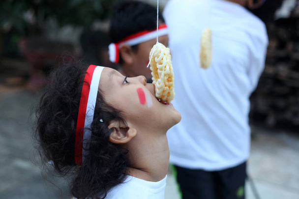 Niños indonesios se están comiendo una competencia de galletas para celebrar el día de la independencia de Indonesia - Foto, imagen
