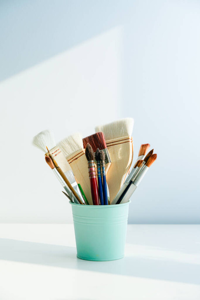 The paintbrush is placed in the barrel. The pen holder and brush are placed in the room with light and shadow - Photo, Image