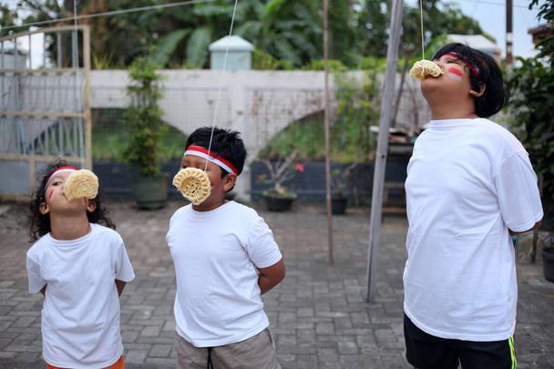 I bambini indonesiani stanno mangiando una gara di cracker per celebrare il giorno dell'indipendenza dell'Indonesia - Foto, immagini
