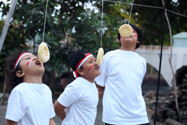 インドネシアの子供たちはインドネシアの独立記念日を祝うためにクラッカー競争を食べています - 写真・画像
