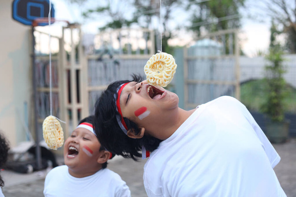Indonesian children are eating a cracker competition to celebrate Indonesia's independence day - Photo, Image