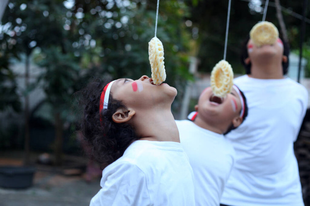 インドネシアの子供たちはインドネシアの独立記念日を祝うためにクラッカー競争を食べています - 写真・画像