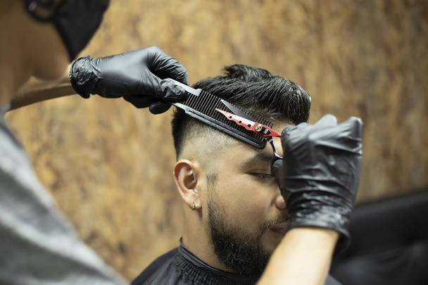 hairdresser's hands cutting hair with scissors to a man - Photo, Image