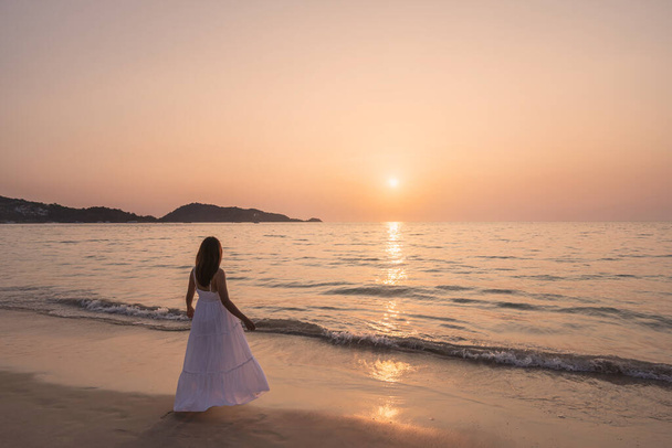 Самотня молода азіатка, що стоїть на пляжі на заході сонця
 - Фото, зображення