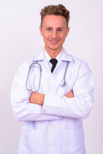 Studio shot of handsome man doctor with blond curly hair against white background - Foto, Imagen