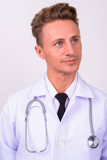 Studio shot of handsome man doctor with blond curly hair against white background - Foto, immagini