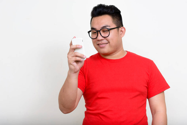 Studio shot of young handsome overweight Filipino man against white background - Фото, изображение