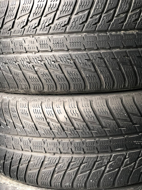  Una gran cantidad de neumáticos usados viejos se encuentran uno encima del otro. Sustitución de neumáticos de invierno y verano. Concepto de reemplazo estacional de neumáticos - Foto, imagen