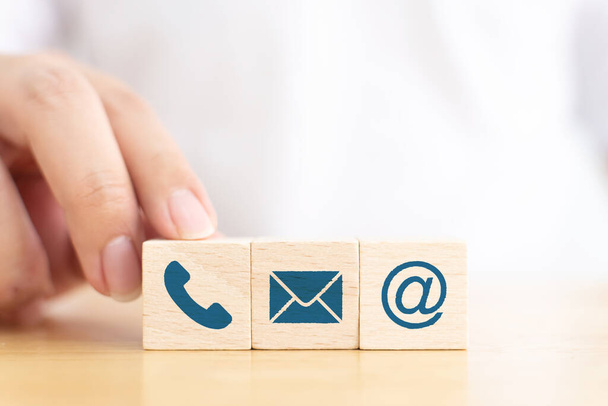 Businessman hand choose wooden block cube symbol icon telephone, envelope email and address sign. Website page contact us or e-mail marketing concept - Photo, Image