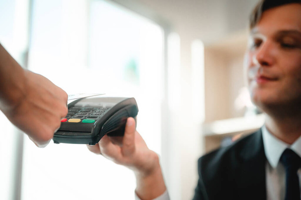 Πελάτης πληρώνει χρήματα με ανέπαφη πιστωτική κάρτα με την τεχνολογία NFC. Επιχειρηματίας κρατώντας μηχάνημα ανάγνωσης πιστωτικών καρτών - Φωτογραφία, εικόνα