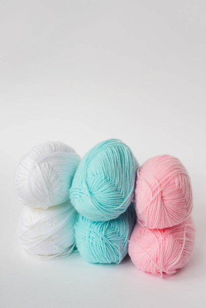 acrylic soft pastel pink, azure and white colored wool yarn thread skeins row on white background, side view, vertical stock photo image with copy space for text - Zdjęcie, obraz