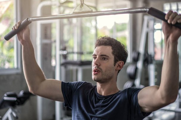 Hübscher Gewichtheber beim Hantelheben mit Squats-Schmied-Maschine beim Training im Fitnessstudio. - Foto, Bild