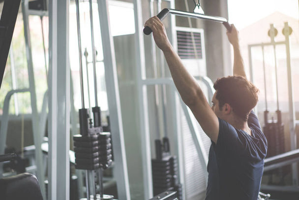 Guapo levantador de pesas levantando pesas con la máquina Squats smith trabajando en el gimnasio
. - Foto, Imagen