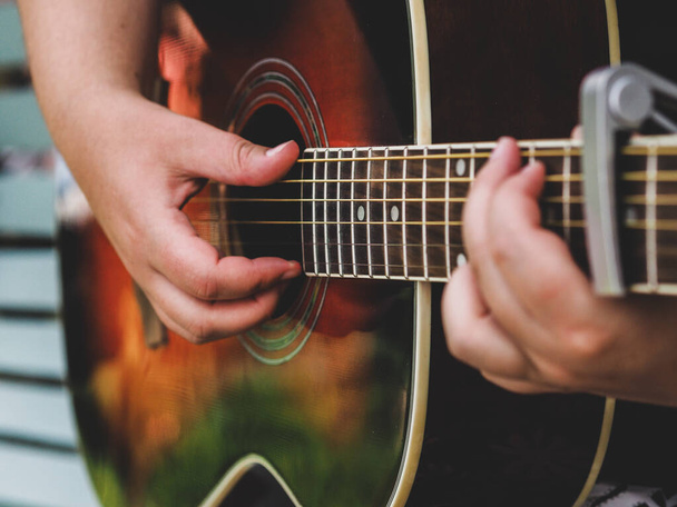 акустическая гитара играет вблизи шеи руки пальцы музыканта - Фото, изображение