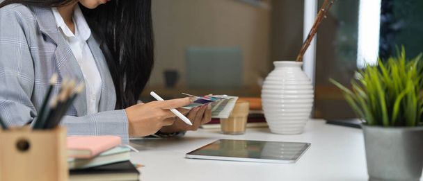 Oldalnézet a női dolgozó okostelefon és tabletta irodai asztal irodai szobában - Fotó, kép