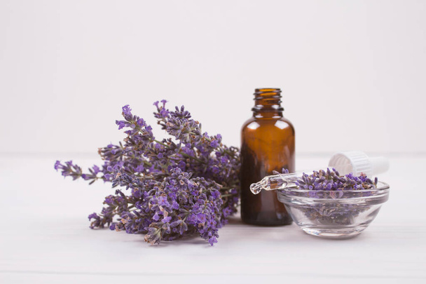 Dropper bottle with lavender essential oil and lavender flowers on white background with copyspace for text. Trendy toned photo for your blog or presentation, mockup - Photo, Image